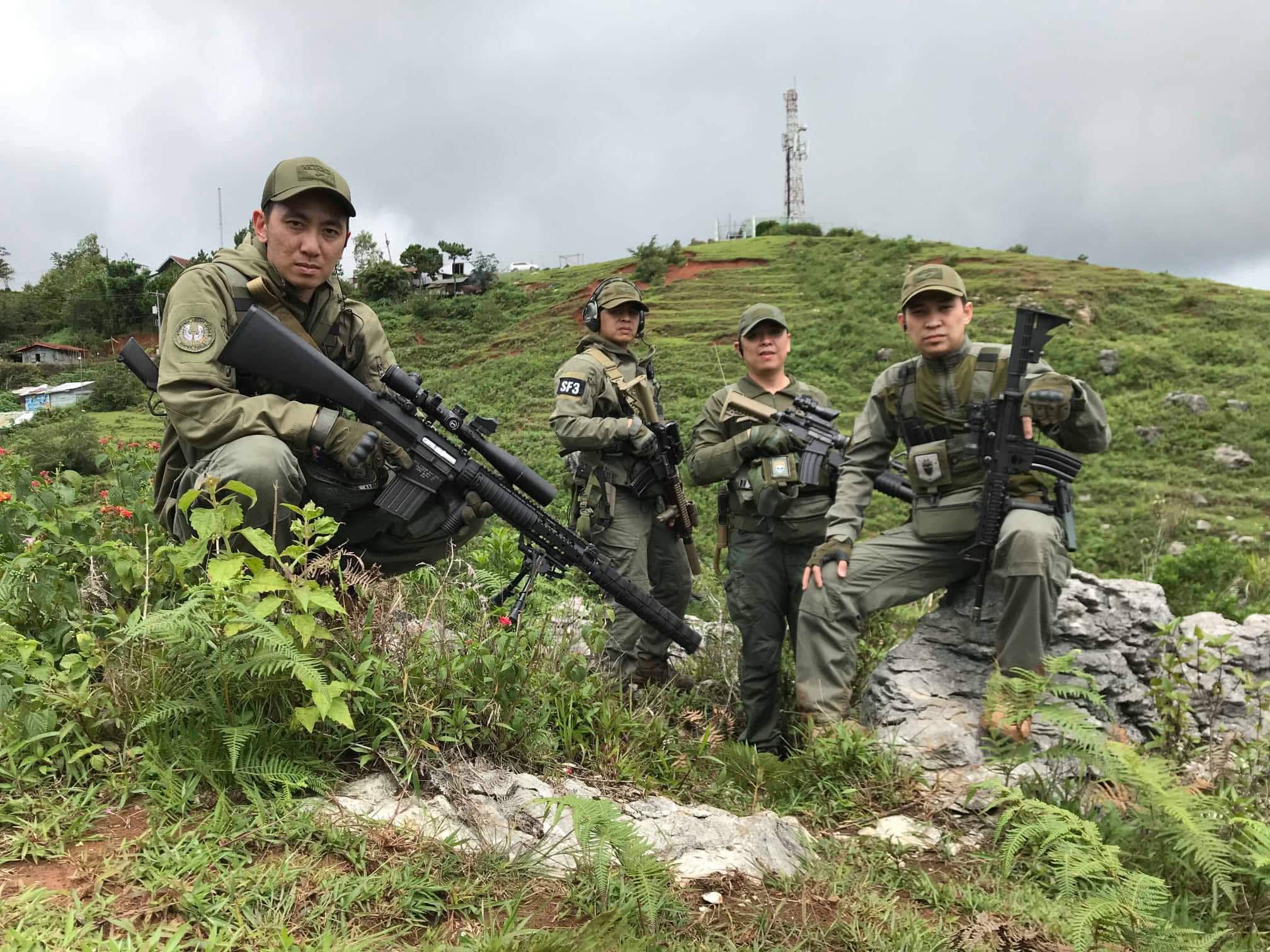 A four-member element holds high ground under overcast skies.