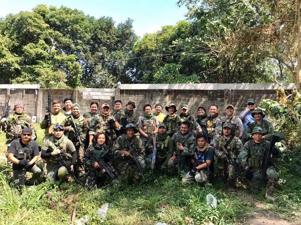 Members line up along a perimeter wall for a group photo.