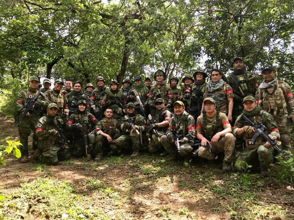 The roster poses in the jungle wearing red identifying armbands.